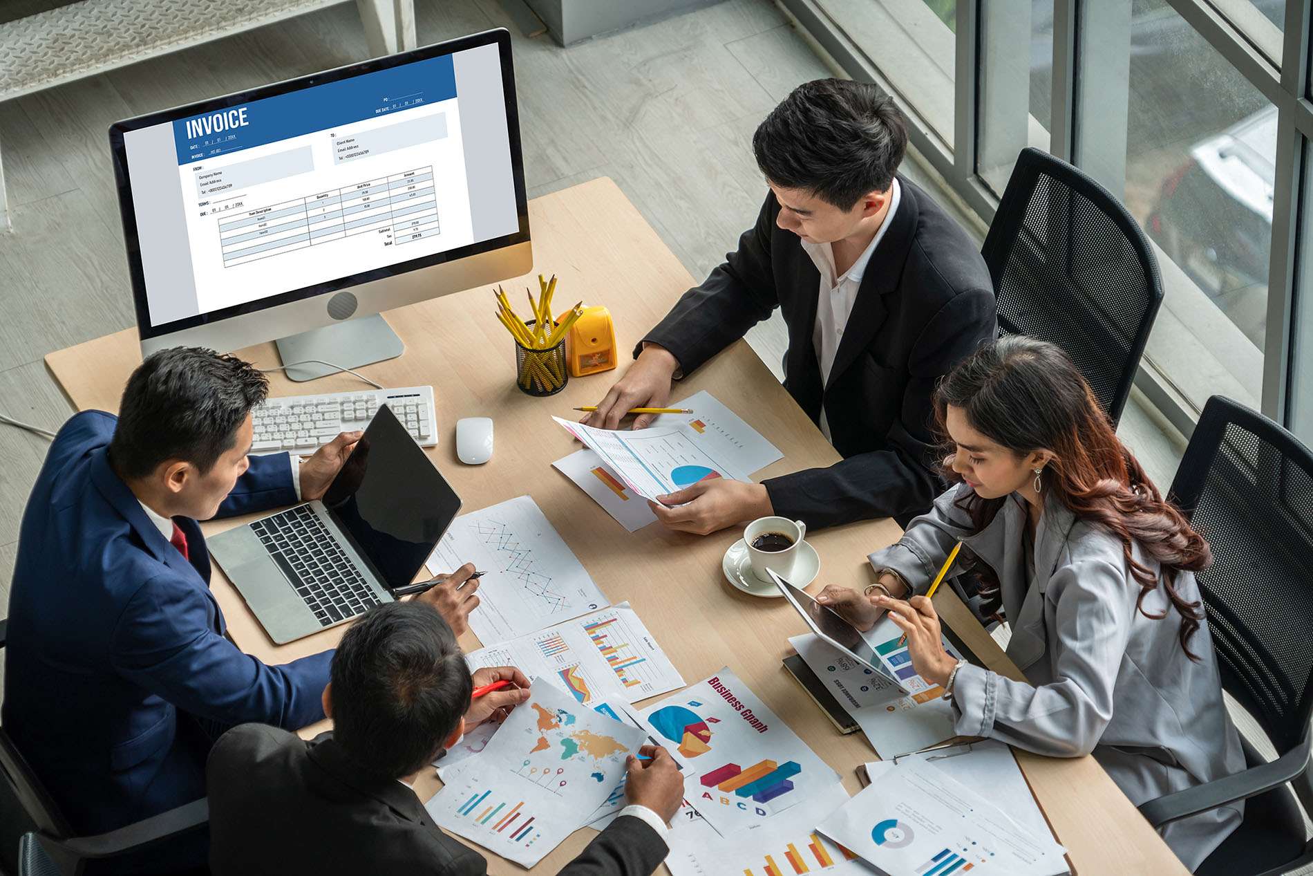 Four colleagues reviewing reports and data on a laptop during a meeting